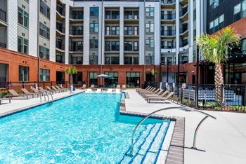 A swimming pool with chairs and a building in the background